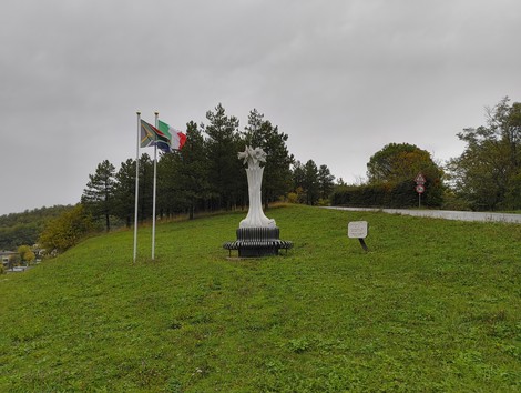 Monumento ai soldati sudafricani, simbolo di memoria e riconoscenza, circondato da bandiere e natura.