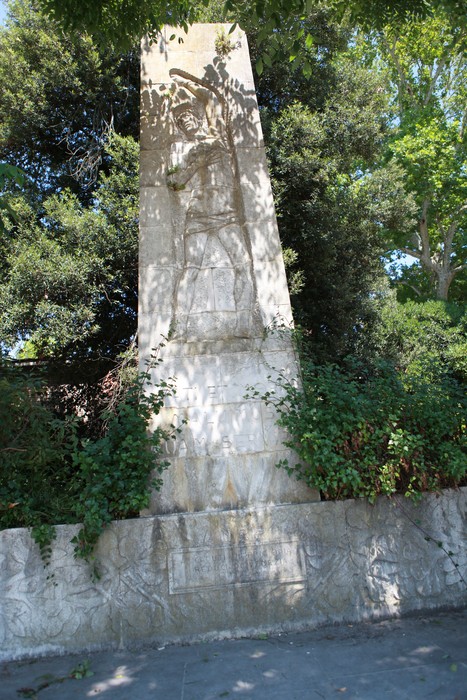 Monumento ai militari caduti in prigionia, caratterizzato da rilievi e un design imponente, immerso nel verde.