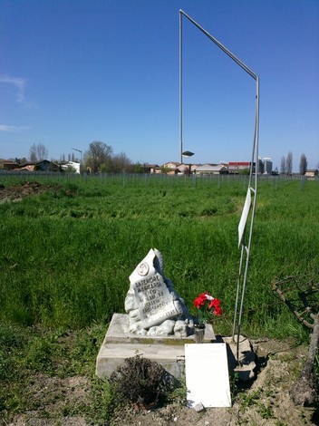 Cippo a Manicardi, monumento dedicato alla memoria, immerso in un paesaggio rurale.