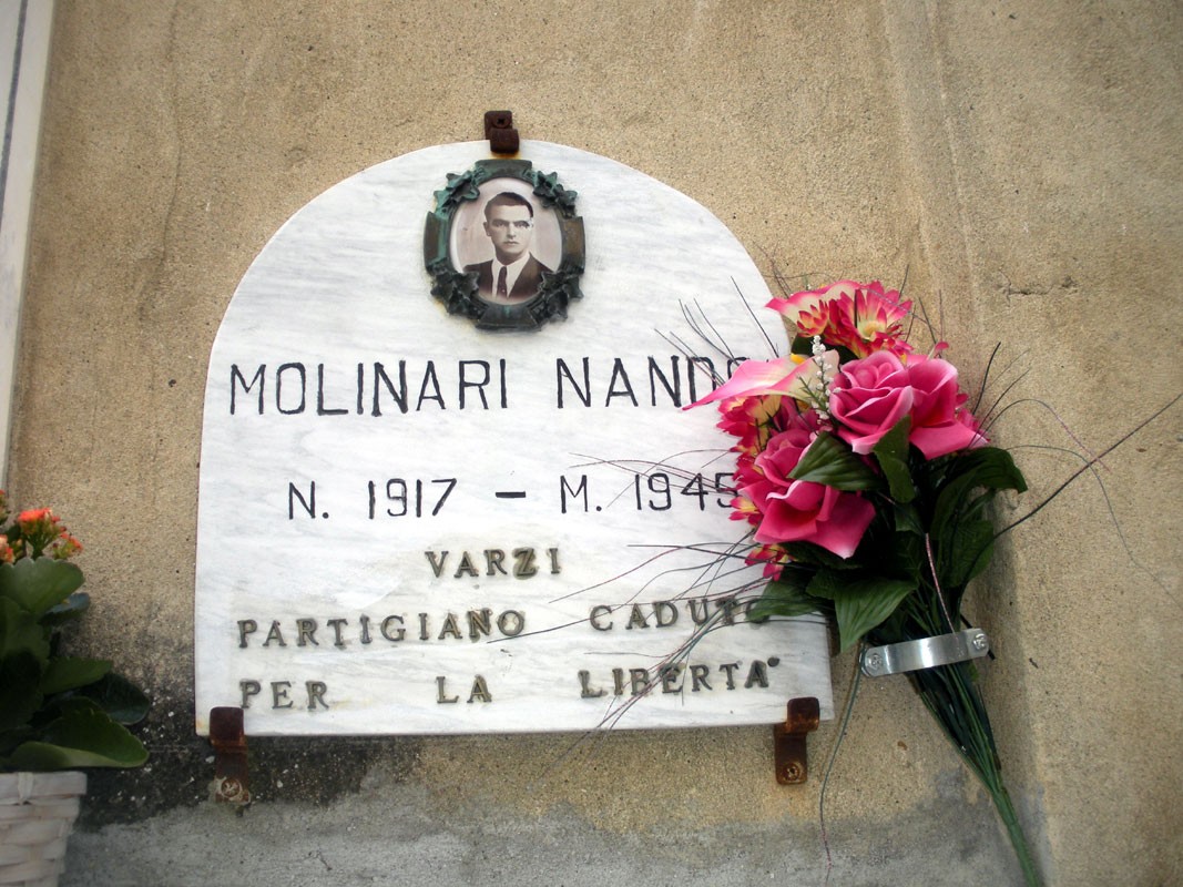 Lapide commemorativa di Nando Molinari, partigiano caduto per la libertà, decorata con fiori.