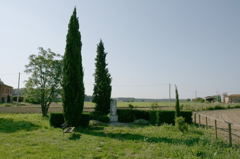 Monumento di Prato Grande, immerso nel verde, circondato da cipressi e paesaggio rurale.