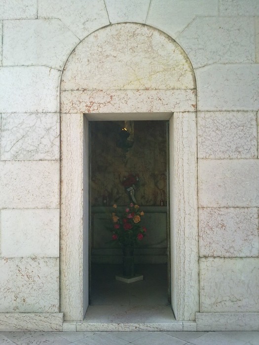 Ingresso del Sacrario dei caduti per la Liberazione di Luzzara, con decorazioni floreali e architettura sobria.