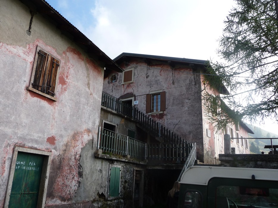 Edificio rustico con pareti scrostate e balconi in legno, immerso in un ambiente montano.