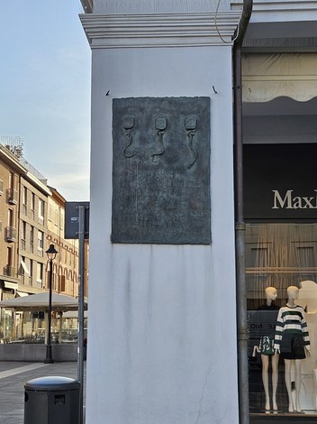 Targa commemorativa dei Tre Martiri su una parete di un edificio, con dettagli artistici e storici.