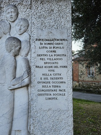 Monumento alla Resistenza, pietra scolpita con figure umane e fiori, simbolo di lotta e libertà.