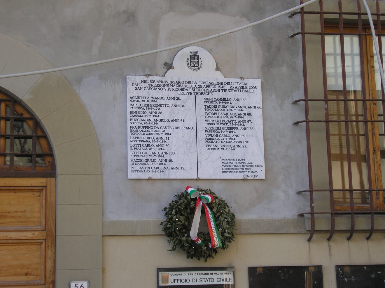 Lapide del Municipio con iscrizioni commemorative e una corona di alloro decorata.
