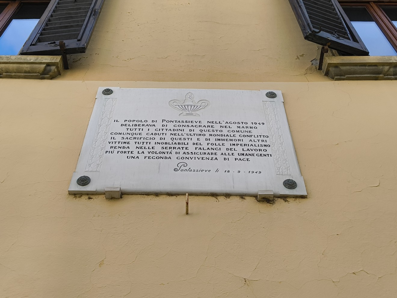 Lapide commemorativa per onorare i caduti, situata a Pontassieve, con messaggio di pace e memoria storica.