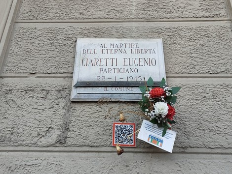 Lapide commemorativa di Eugenio Giaretti, partigiano, con decorazioni floreali e un codice QR.