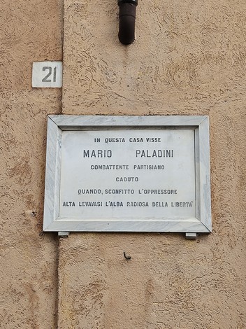 Lapide commemorativa di Mario Paladini, partigiano, situata su una parete esterna di un edificio.