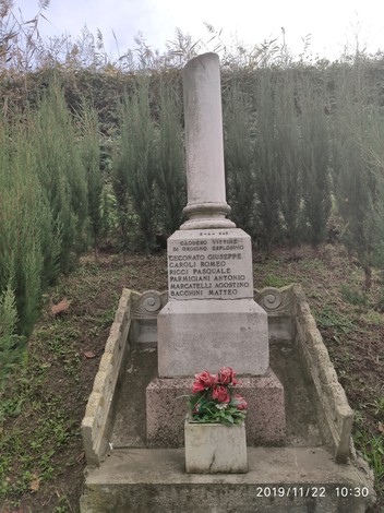 Monumento commemorativo a Ceconato, dedicato a Giuseppe Caroli e altri, adornato con fiori.