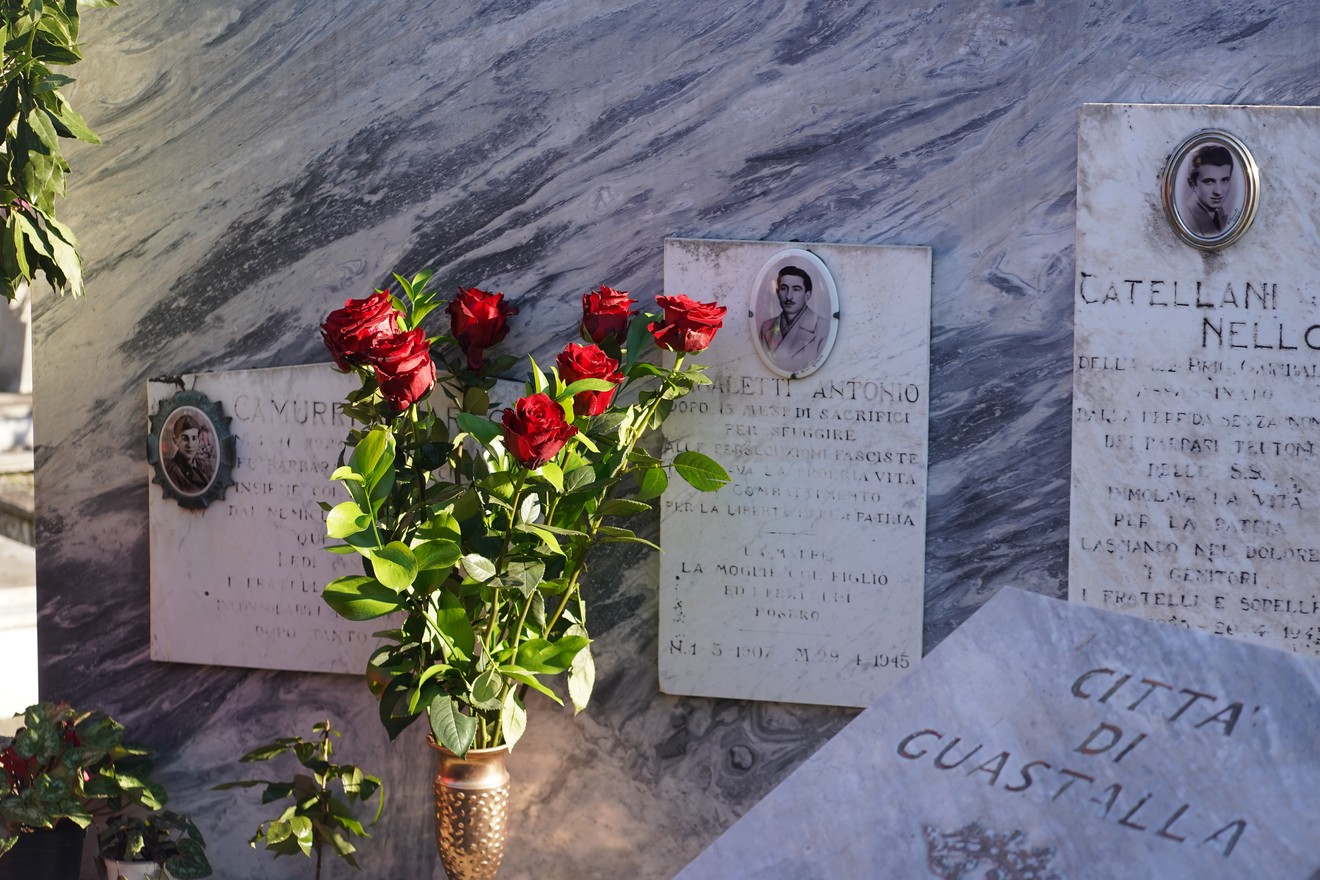 Sepolcri con decorazioni floreali e lapidi commemorative nel cimitero di Guastalla.