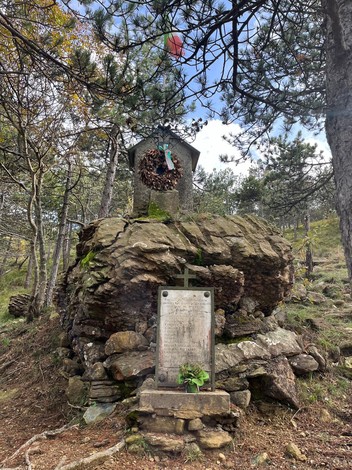 Sacrario ai Martiri di Passo Mezzano, monumento in pietra circondato da una vegetazione boschiva.