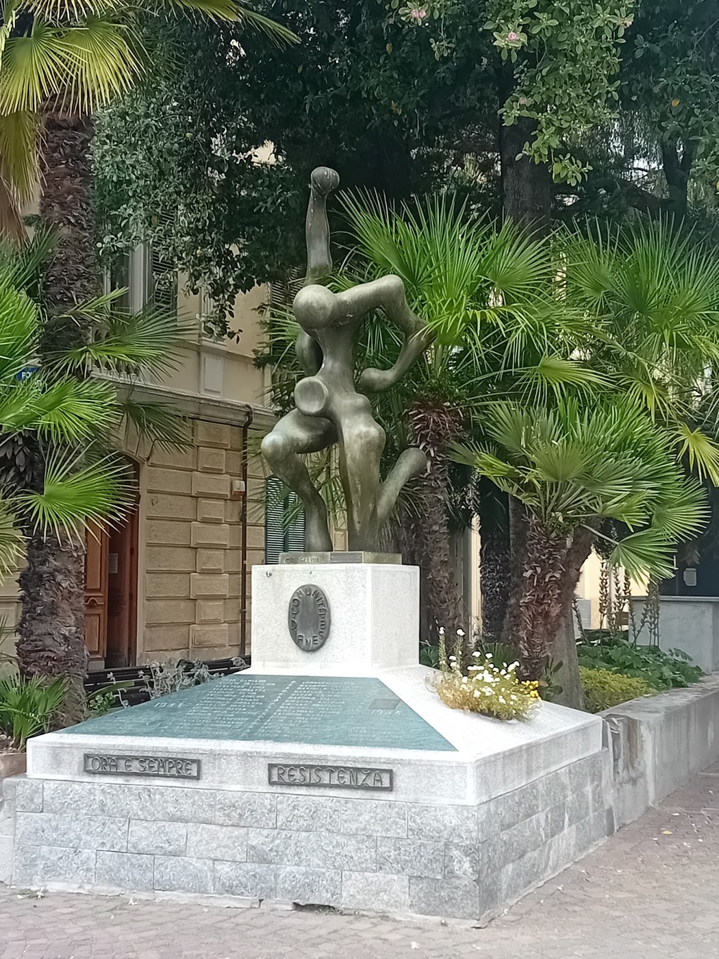 Monumento alla Resistenza, scultura moderna circondata da palme e vegetazione, in un contesto urbano.