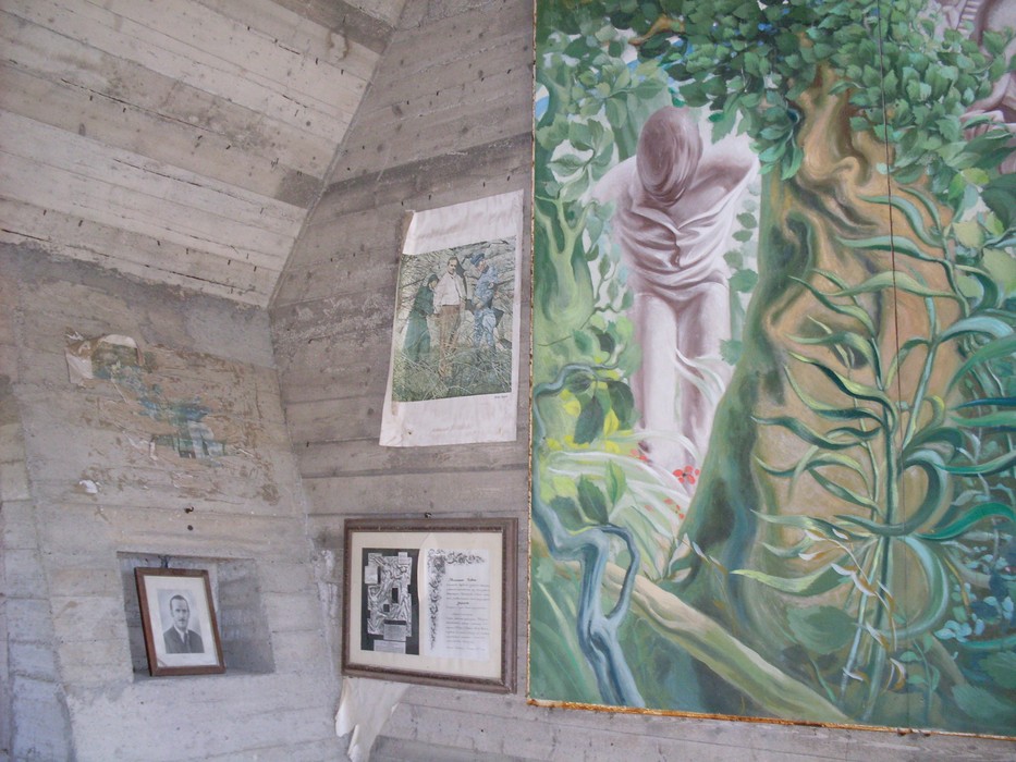 Interno del Monumento ai partigiani, con opere d'arte e mura in cemento che commemorano la Resistenza.
