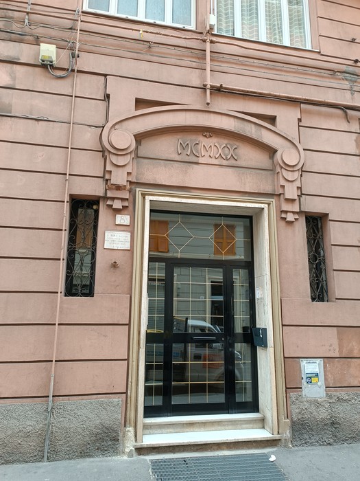 Lapide commemorativa a De Palo su un edificio storico, con dettagli architettonici caratteristici.