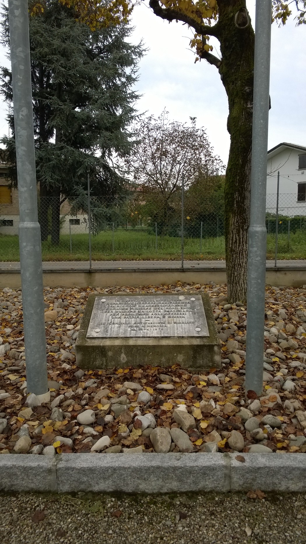 Lapide commemorativa al Comando militare del Nord-Emilia, con contesto naturale e pavimentazione in pietra.
