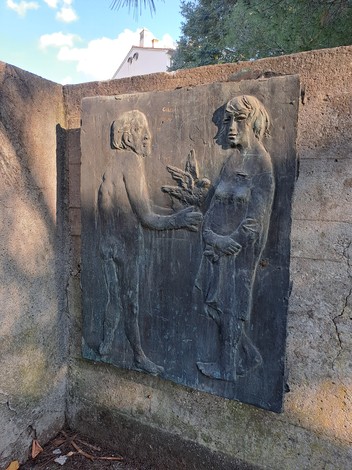 Scultura del "Monumento ai Caduti" con figure umane che interagiscono, simbolo di commemorazione e memoria.