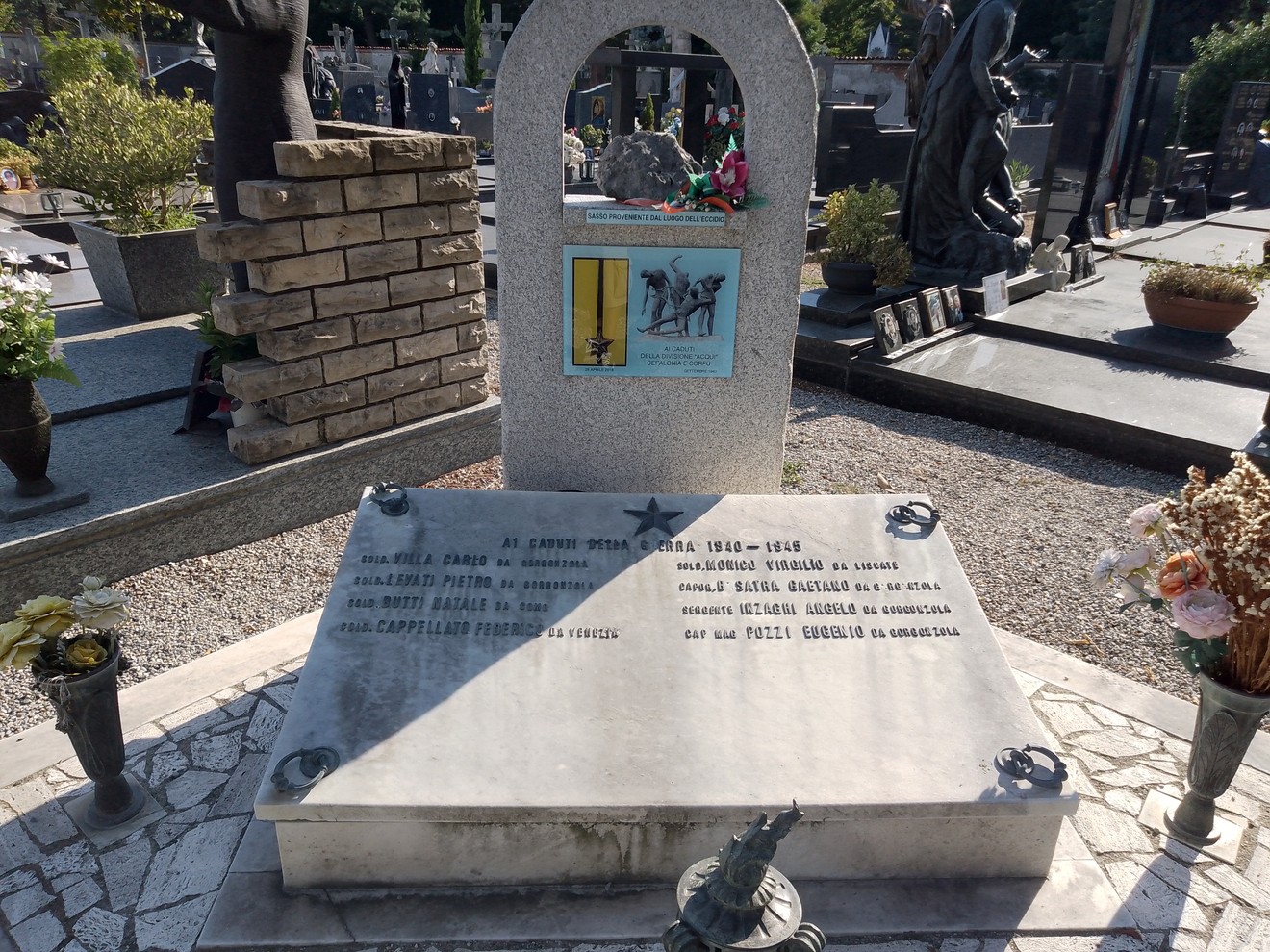 Monumento ai caduti della Divisione Acqui, commemorazione con lapidi e fiori in un cimitero.