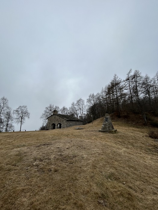Monumento ai partigiani su una collina, circondato da alberi in un paesaggio grigio e invernale.