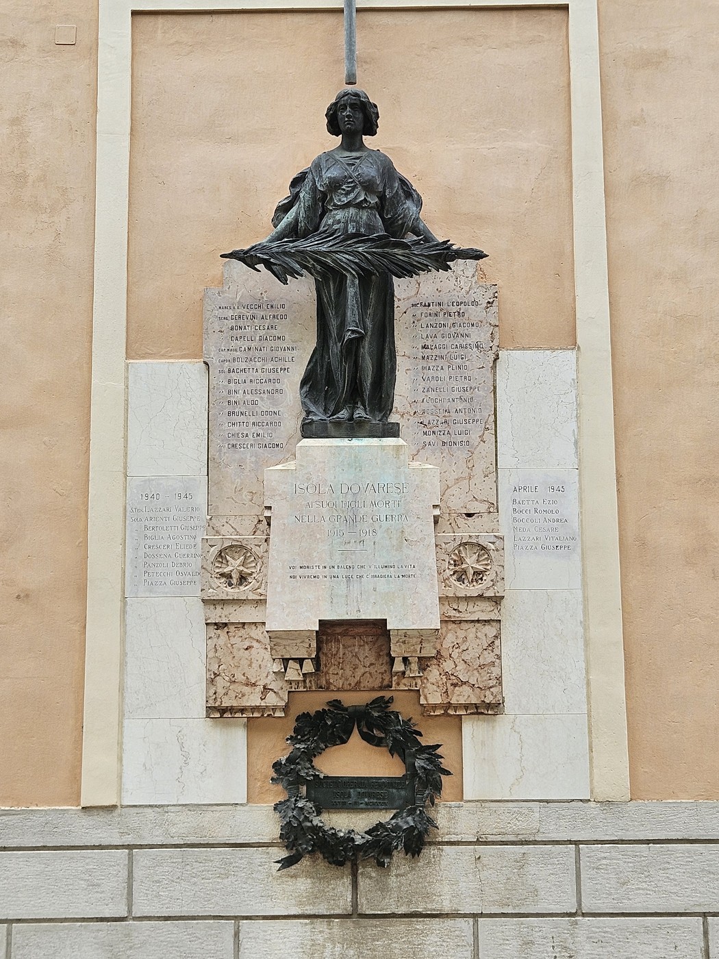 Lapide commemorativa con scultura che onora i caduti di Isola Dovarese, decorata con una corona di alloro.