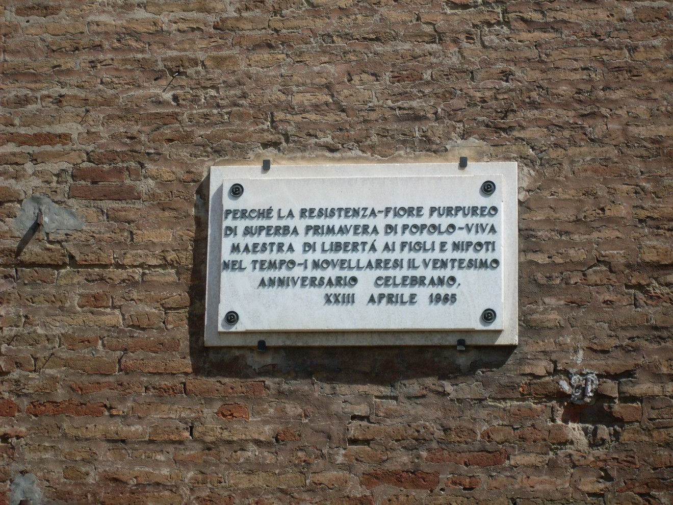 Lapide che celebra la Resistenza, simbolo di libertà e sacrificio, installata in un contesto storico significativo.