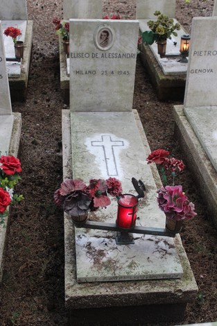 Tombe adornate con fiori e candele, in memoria dei caduti per la Libertà. Atmosfera di rispetto e commemorazione.