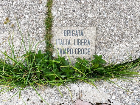 Monumento al Partigiano, simbolo della Resistenza italiana, con erba e pavimentazione evidente.