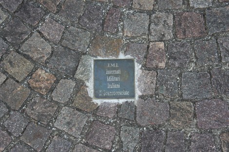 Pietra d'inciampo in memoria dei partigiani, incastonata tra i ciottoli di una pavimentazione.