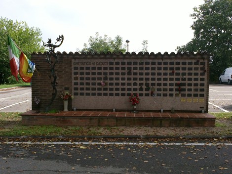 Monumento commemorativo ai caduti, situato a Gattatico, con decorazioni floreali e bandiere.