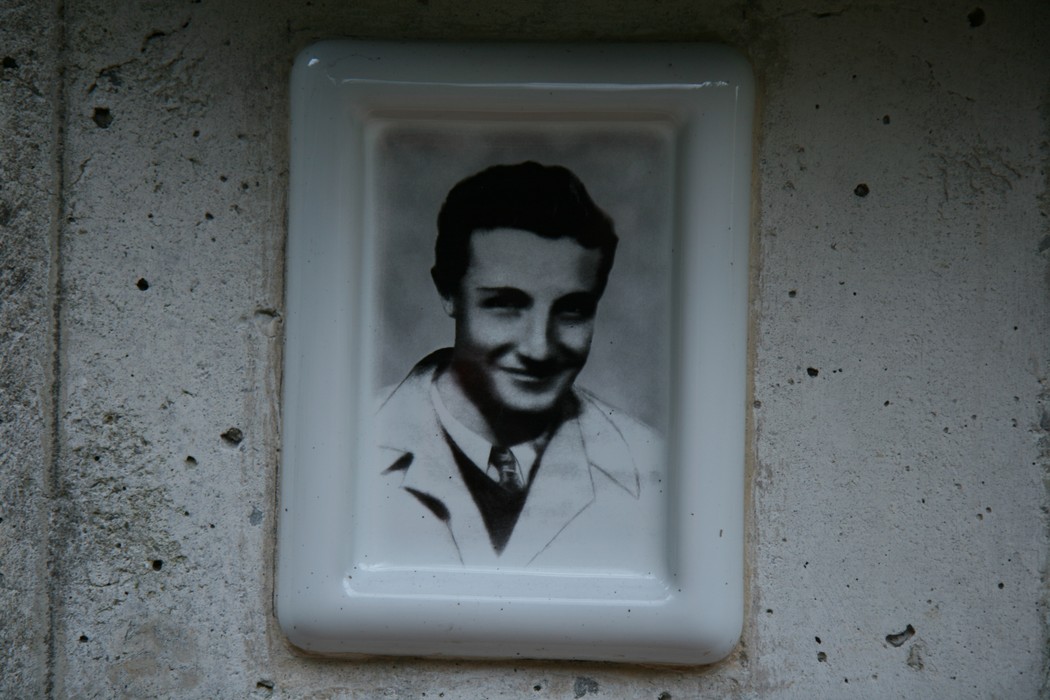 Monumento a Santini: una targa commemorativa con un'immagine in bianco e nero di un giovane.