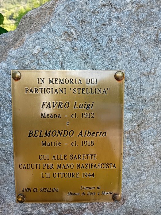 Cippo commemorativo dedicato ai partigiani Favro e Belmondo, situato in un contesto naturale.