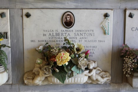 Sepolcro di alberta santoni, vittima di un bombardamento nel 1944, adornato con fiori e decorazioni.