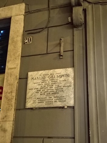 Lapide commemorativa a Manlio Gelsomini, con dettagli artistici e storici, situata su un edificio.