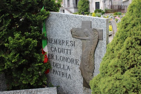 Tomba dedicata ai caduti per la patria, con decorazioni e un angelo in rilievo su una lapide di granito.