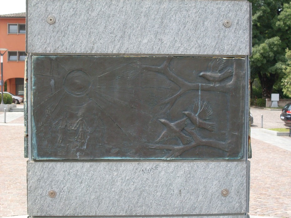 Monumento alla pace con rilievi in bronzo e pietra, simbolo di armonia e unità.