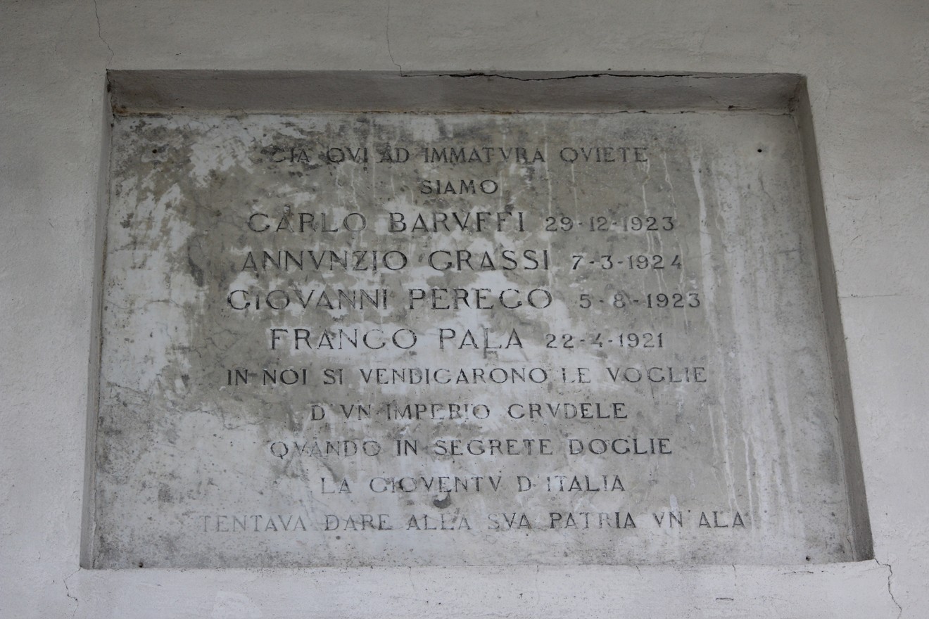 Lapide commemorativa dedicata a Baruffi, Grassi, Perego e Pala, situata in un ambiente monumentale.