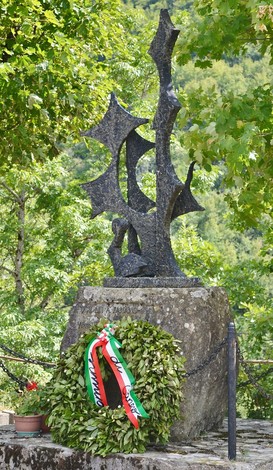 Monumento dedicato a Bonucchi, Tonioni e Venturelli, con una corona di alloro e un paesaggio verde circostante.