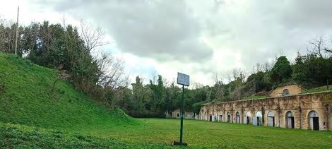 Monumento di Forte Bravetta, zona verde con mura storiche e un cielo nuvoloso. Tranquillità e paesaggio suggestivo.