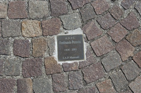 Pietra d'inciampo dedicata a Ferdinando Pezzotta, partigiano, posata sul pavimento in pietra.