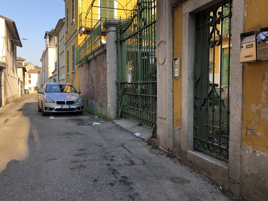 Fotografia di una strada con un'auto parcheggiata e una pietra d'inciampo dedicata a Cagnoni.