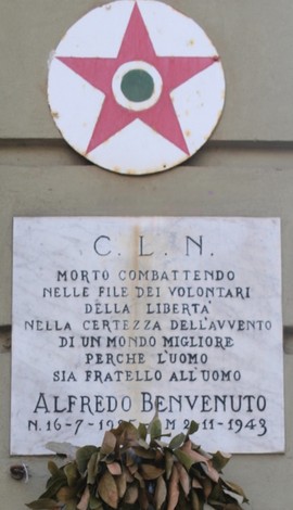 Lapide commemorativa dedicata a Benvenuto, con simbolo e messaggio di libertà e fratellanza.