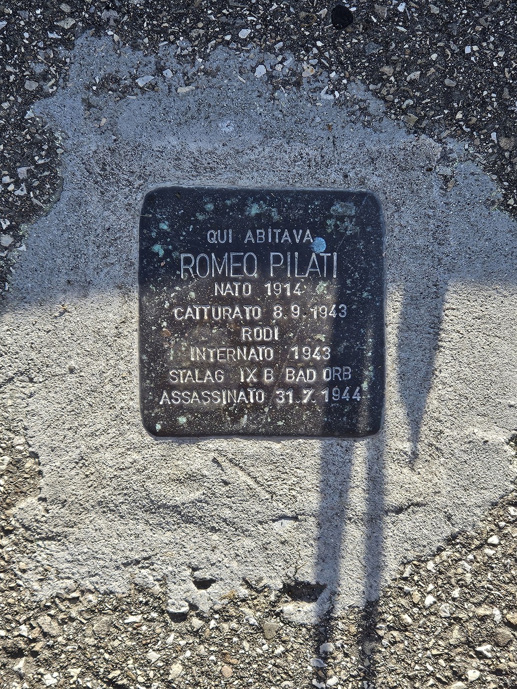 Pietra d'inciampo in metallo scuro incassata nel pavimento, con iscrizione commemorativa.