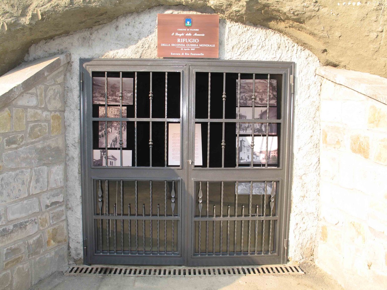 Entrata del Rifugio di guerra di Pianoro, con cancello e pareti in pietra, che conserva la memoria storica.