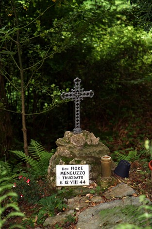 Croce commemorativa dedicata a Don Menguzzo, situata in un'incantevole area naturale.