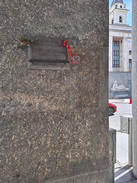 Lapide commemorativa a Martorelli, collocata su un muro di pietra, con decorazioni floreali e un QR code.