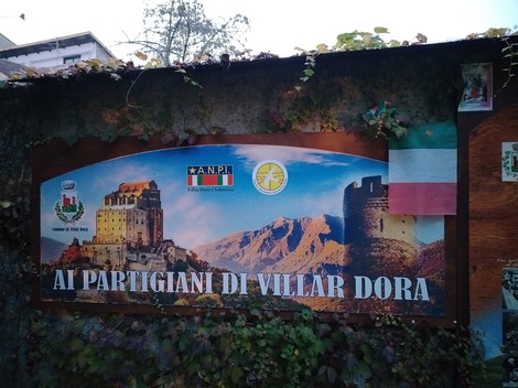 Giardino memoriale a Blandino con pannello commemorativo dedicato ai partigiani di Villar Dora, circondato da natura.