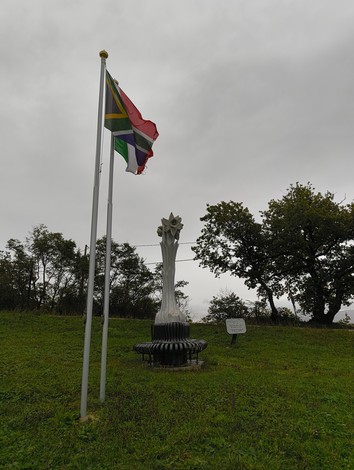 Monumento ai soldati sudafricani, con bandiera e struttura commemorativa in un contesto naturale.