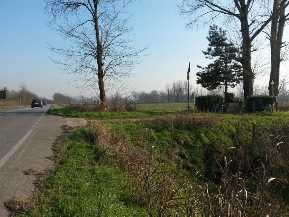 Monumento a Muzio, visibile in un paesaggio rurale con alberi e una leggera nebbia.