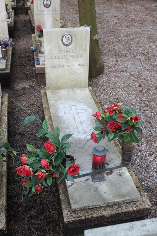 Tombe monumentali con fiori rossi e candele, dedicate ai caduti per la Libertà in un ambiente sereno.
