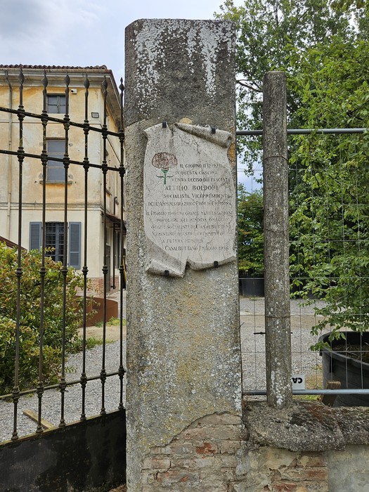 Lapide commemorativa a Boldori, inserita in un contesto storico con vegetazione e architettura circostante.